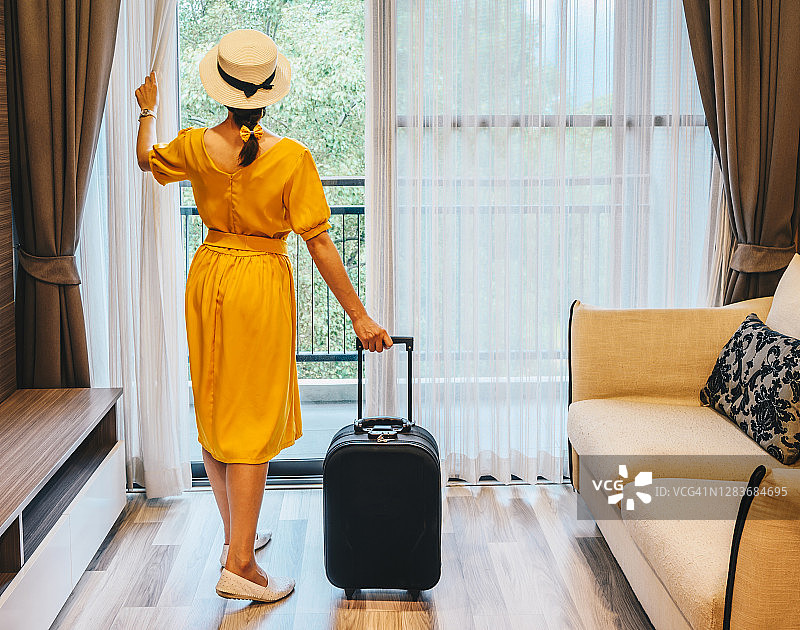 办理入住后，站在窗边欣赏美景的游客女子背影图片素材