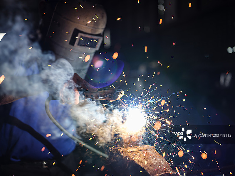 焊接过程中飞溅的火花，焊工佩戴防护头盔面罩图片素材