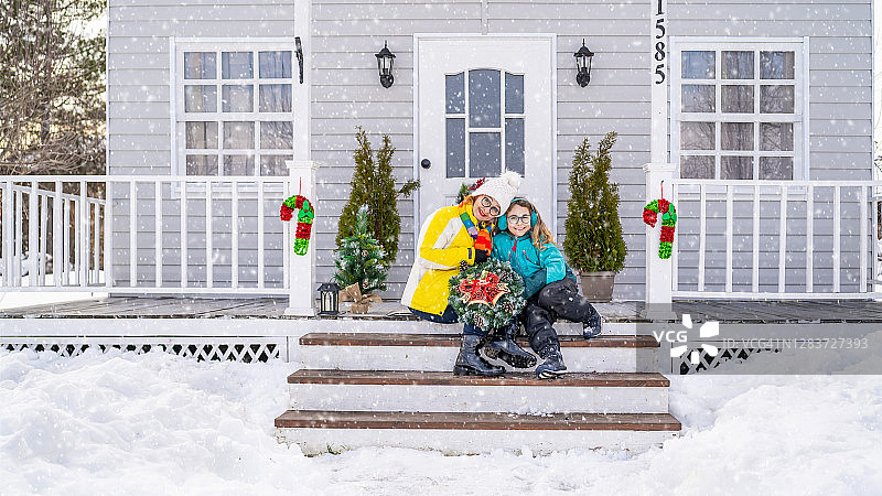母女用圣诞装饰品装饰房屋门廊图片素材