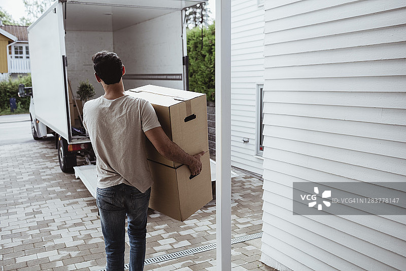 男子搬运纸箱走向货车的背影图片素材