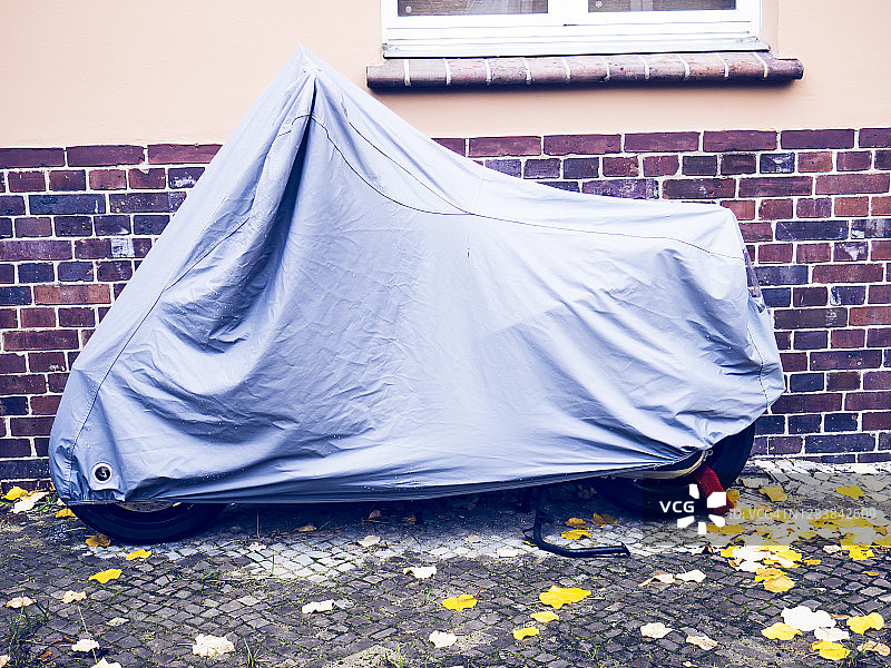 停在柏林街道上，覆盖着保护层的摩托车图片素材