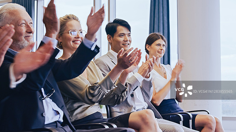 满意的企业家在会议上鼓掌。侧面视角图片素材