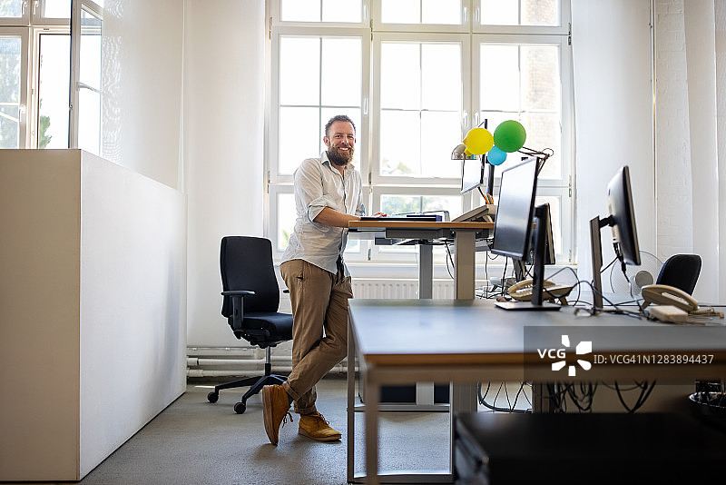 站在办公室人体工学桌旁的商人图片素材