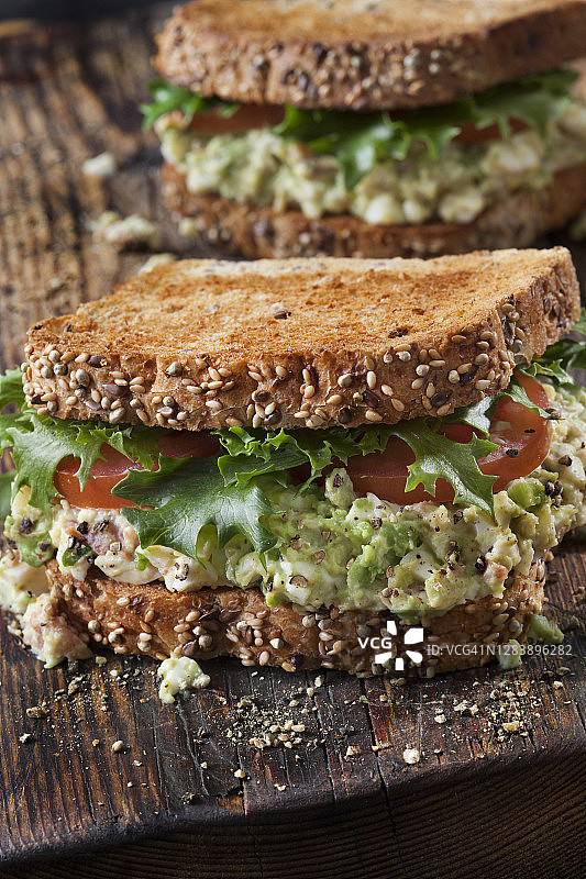 牛油果鸡蛋沙拉三明治配香脆培根，生菜和番茄图片素材