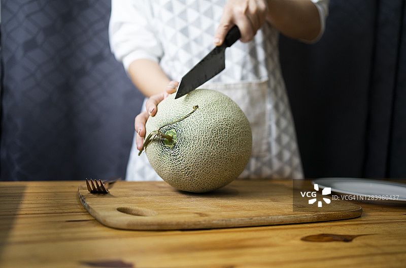 在木桌上切日本甜瓜，带文案空间图片素材