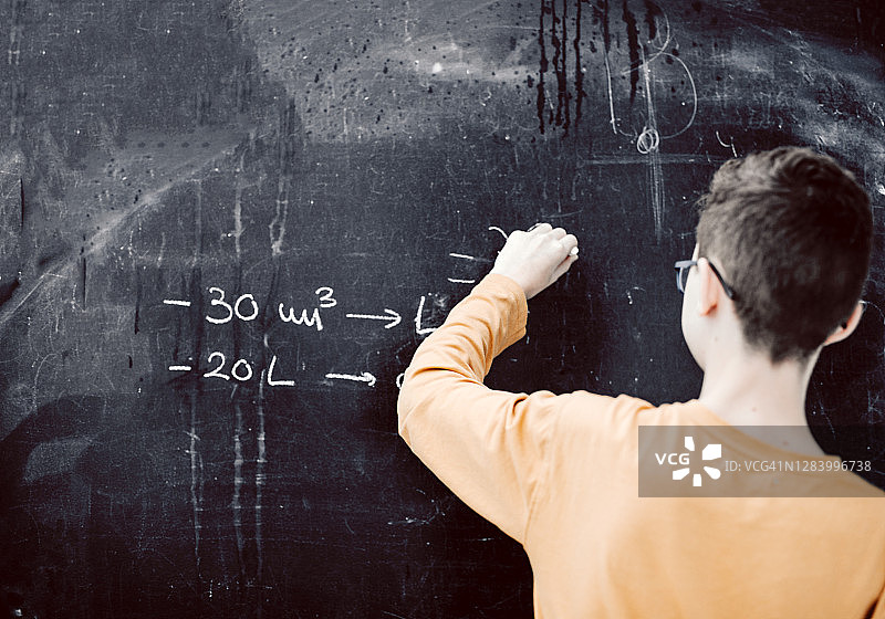 青少年在课堂黑板上做数学题图片素材