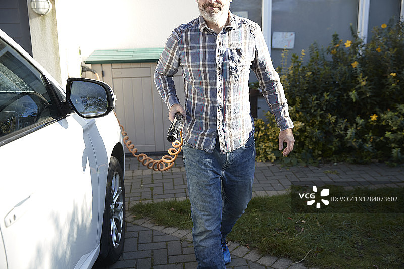 男人在家给电动汽车充电图片素材