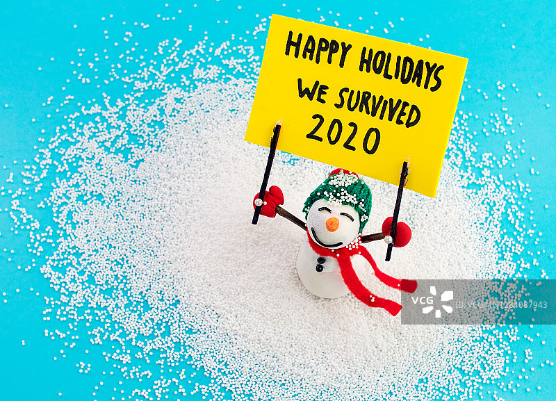 雪人手持横幅，上面写着“节日快乐，我们度过了2020年”图片素材