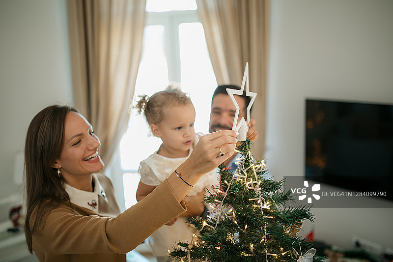 快乐的白人家庭装饰房屋，迎接冬季假期图片素材