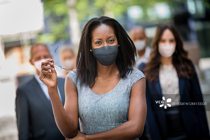 在户外戴着口罩并带领团队的商务女人图片素材