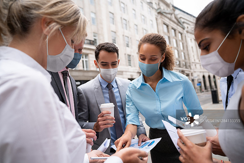 一群戴着口罩的商务人士在户外开会交谈图片素材