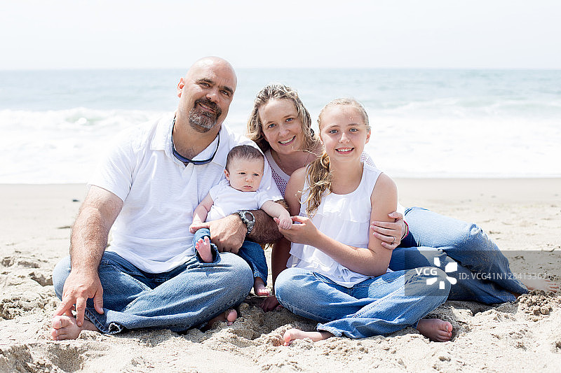 幸福的四口之家坐在沙滩上图片素材