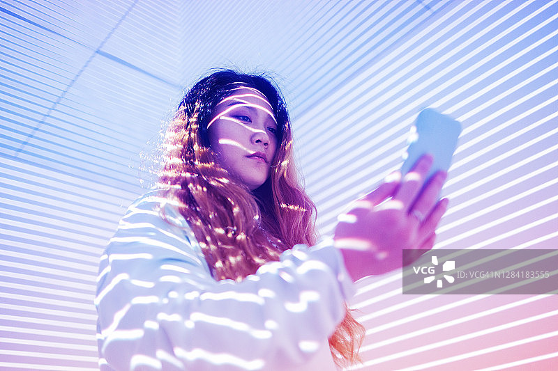 在全息背景下使用手机的女人图片素材