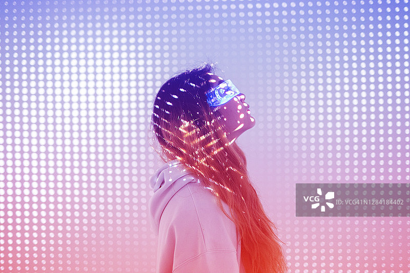 戴着增强现实眼镜站在全息背景中的女人图片素材