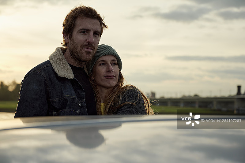 日落时分，年轻夫妇站在车旁环顾四周图片素材