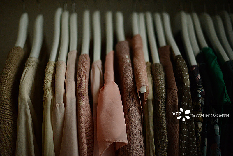 一排排挂在衣架上的衬衫和毛衣，按颜色排列图片素材