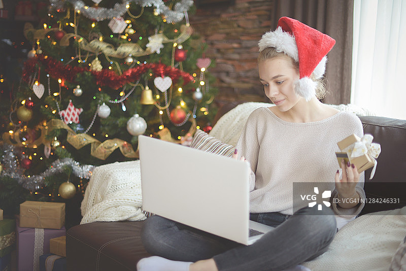 在圣诞节室内使用笔记本电脑的年轻女子 (电子商务)图片素材