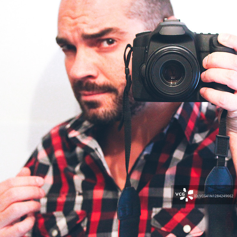 一位用数码单反相机拍照的男人的正面视图图片素材