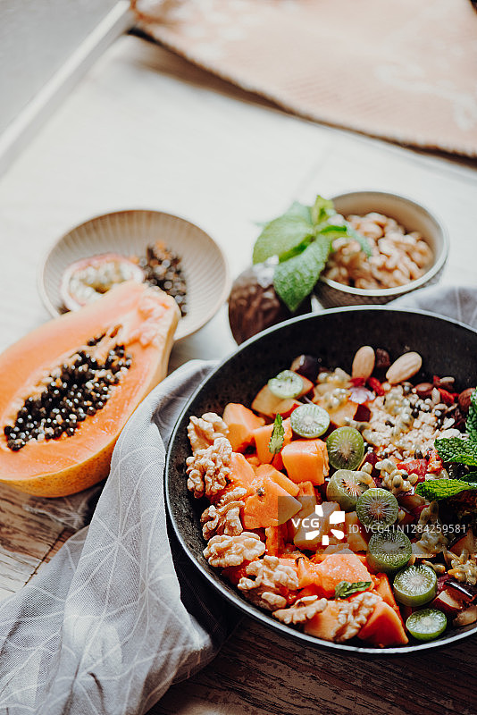 旅途中的美食——木瓜、猕猴桃和百香果思慕雪碗，配以格兰诺拉麦片、核桃和枸杞图片素材