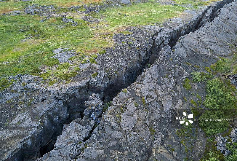 冰岛北部居约塔焦断层带绿色草甸上的黑色裂缝图片素材