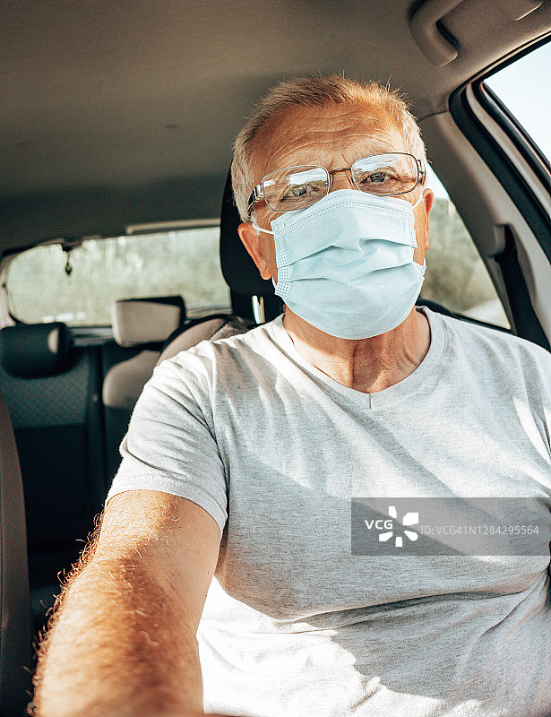 封锁期间男人戴口罩开车图片素材