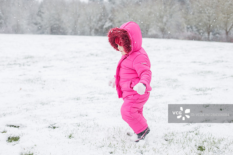 穿着粉色滑雪服，享受雪景的小女孩图片素材