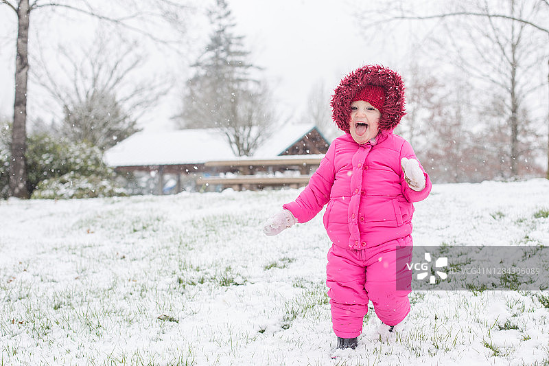 穿着粉色滑雪服，享受雪景的小女孩图片素材