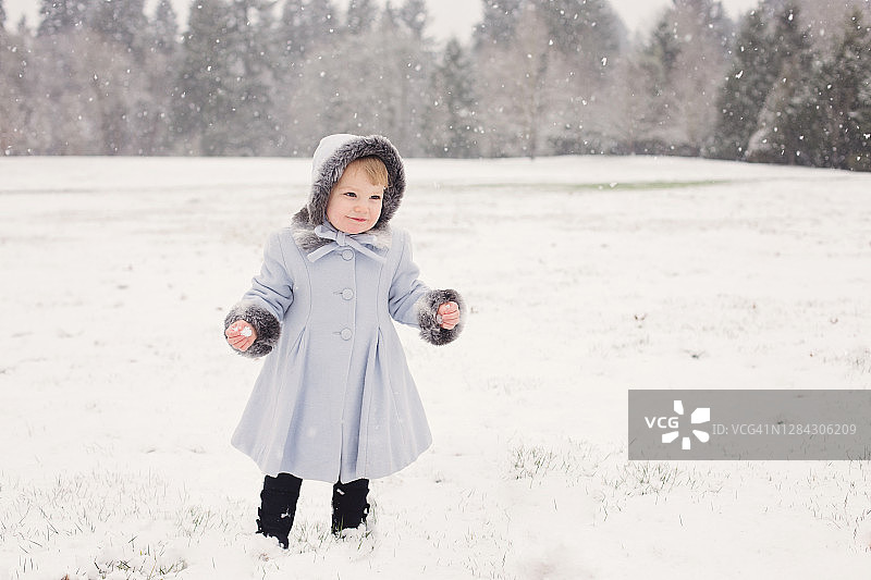 穿着经典外套在雪地里玩耍的小女孩图片素材