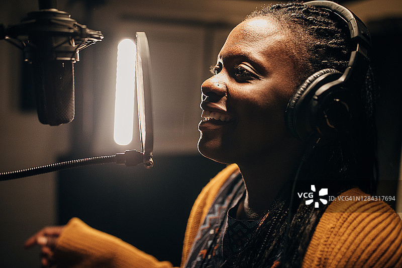 黑人女歌手在录音棚对着麦克风唱歌图片素材