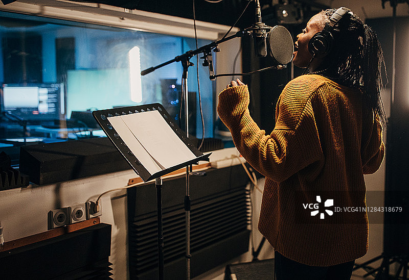 黑人女歌手在录音棚对着麦克风唱歌图片素材