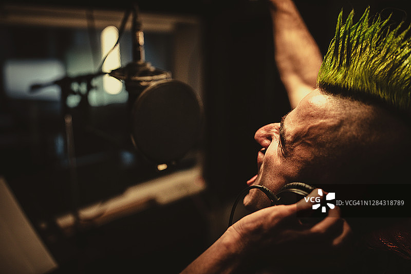 在录音棚里对着麦克风唱歌的朋克男人图片素材