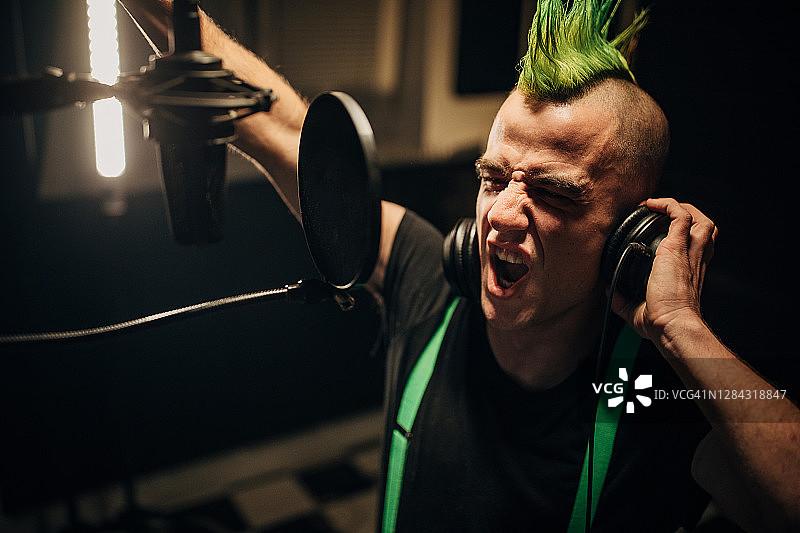 在录音棚里对着麦克风唱歌的朋克男人图片素材