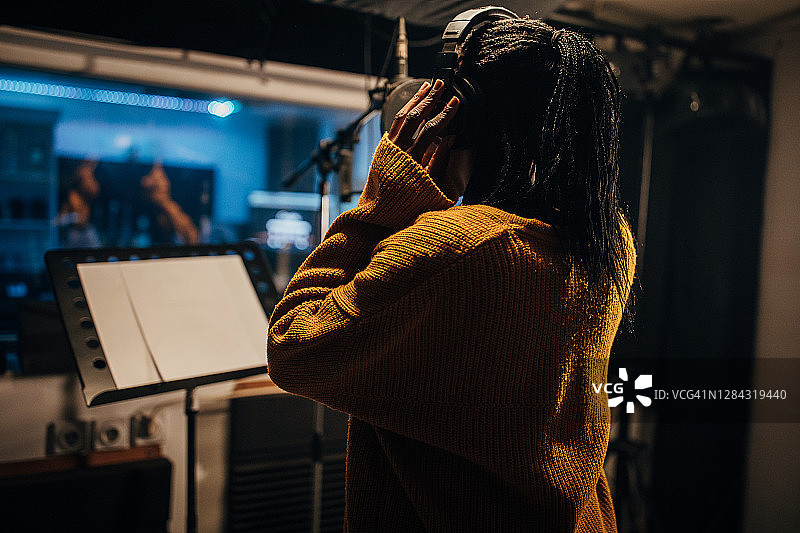 黑人女歌手在录音棚对着麦克风唱歌图片素材