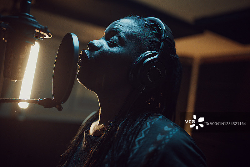 一位美丽的非裔美国女歌手在录音棚录制歌曲图片素材