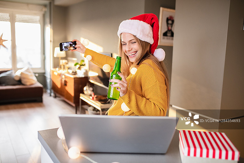 在家与朋友在线庆祝圣诞节并自拍的年轻女人图片素材