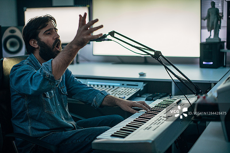 男录音师在录音棚弹奏合成器并歌唱图片素材