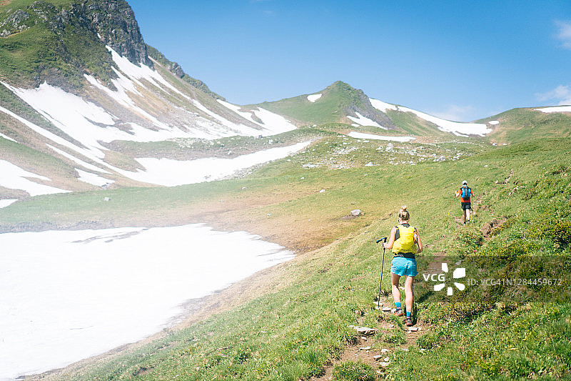 越野跑者穿过高山草甸登上山路图片素材
