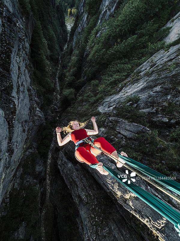 运动型女性在离地面300米的高空表演空中绸缎倒挂图片素材