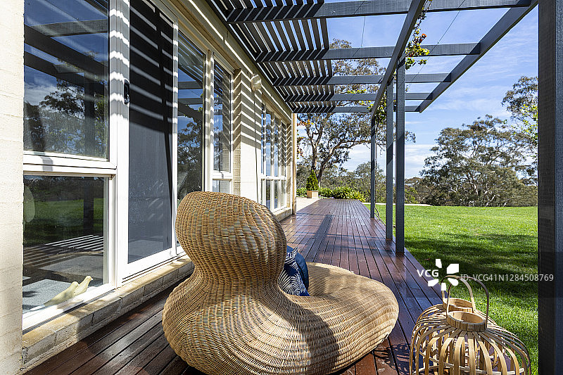 房子前草坪附近木甲板上的甘蔗躺椅图片素材