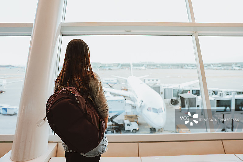 在机场航站楼观看飞机的女人，准备旅行图片素材