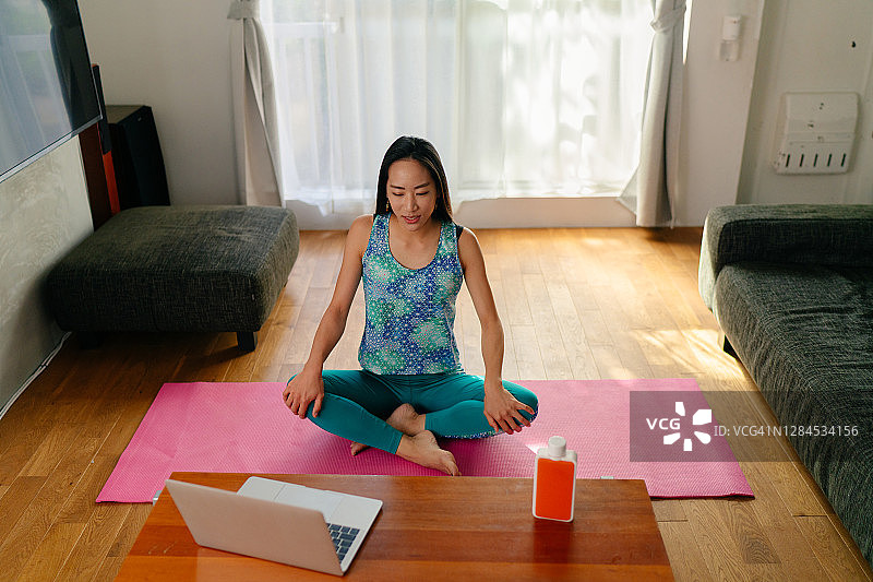 女瑜伽教练在家用笔记本电脑在线教学图片素材