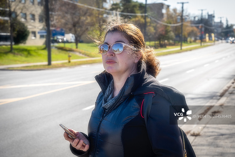 在城市里等待网约车的西班牙裔女人图片素材