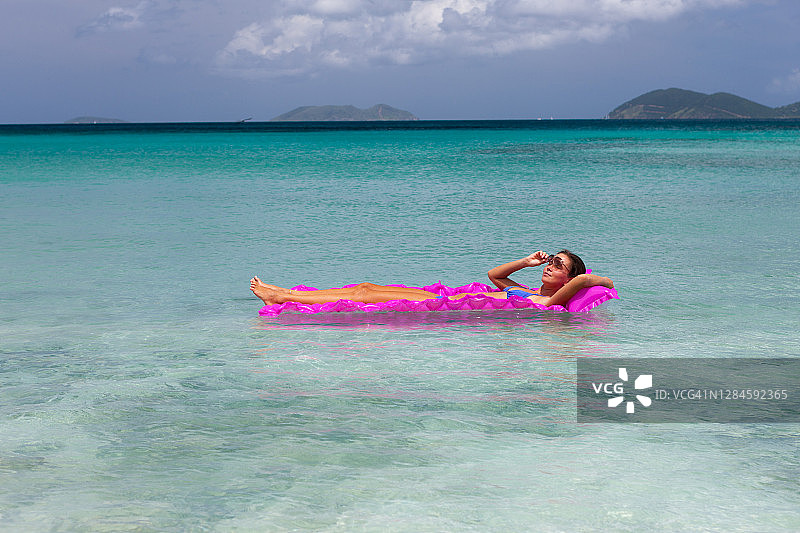 女人在完美的热带海滩的木筏上放松身心图片素材