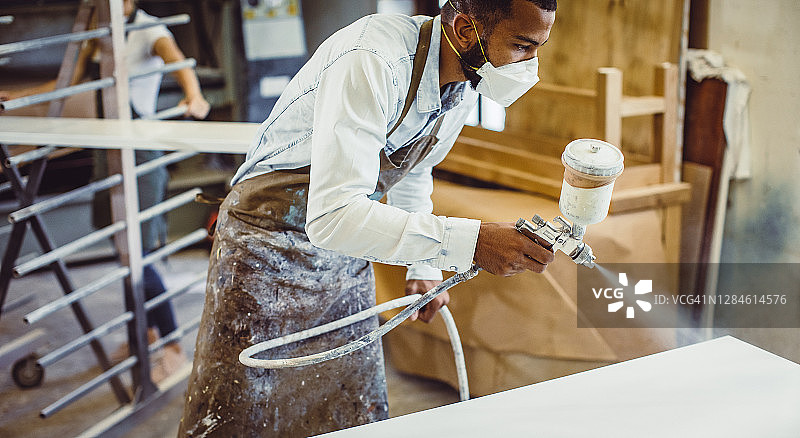 木匠用喷枪喷涂桌子图片素材