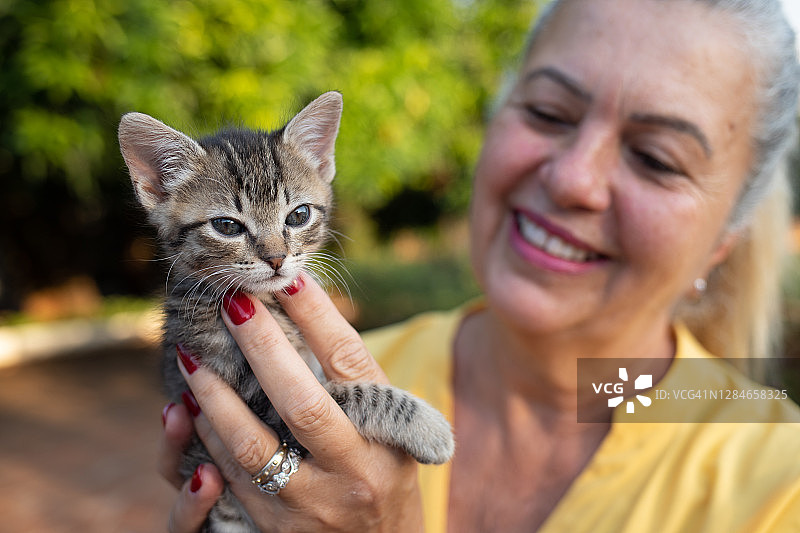 抱着新领养的猫的快乐女人肖像图片素材