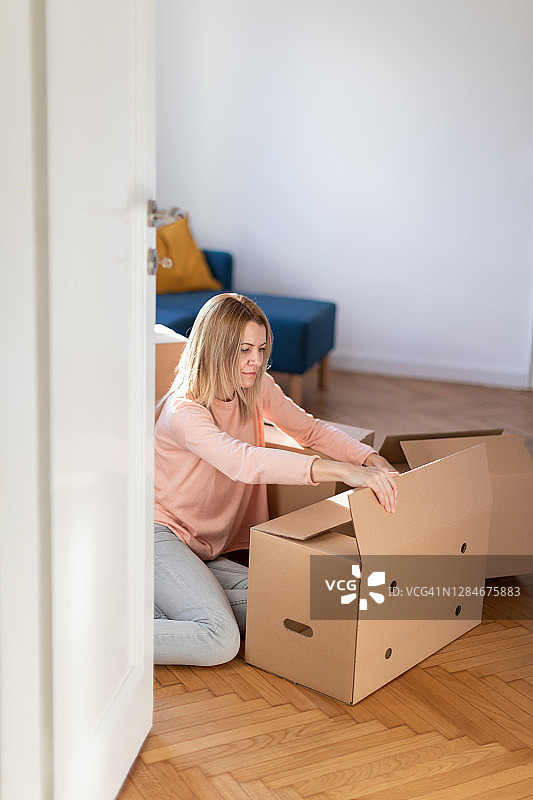 坐在地板上，正在封箱搬家的女人图片素材