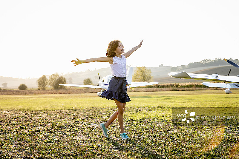 张开双臂站在机场跑道的小女孩图片素材