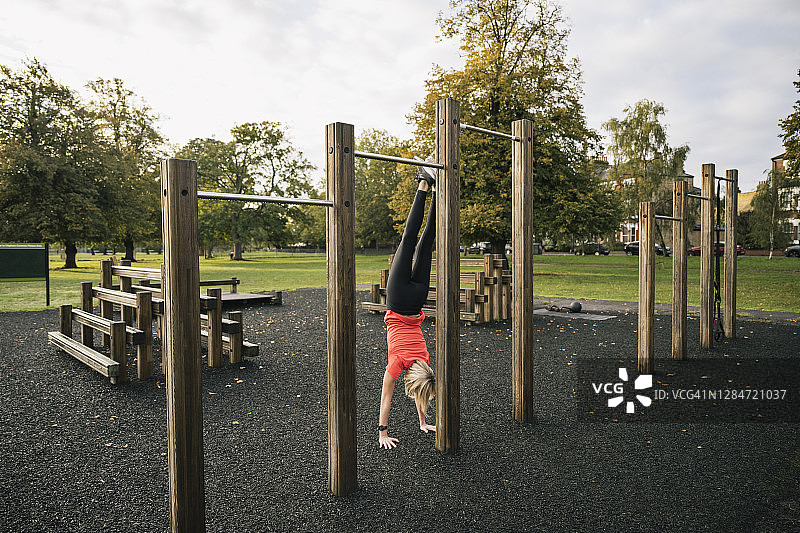 在户外健身场所做倒立的中年女运动员图片素材