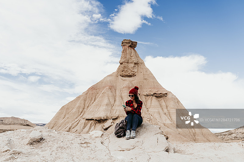 西班牙纳瓦拉：女游客在巴尔德纳斯雷亚莱斯砂岩岩层前使用智能手机图片素材