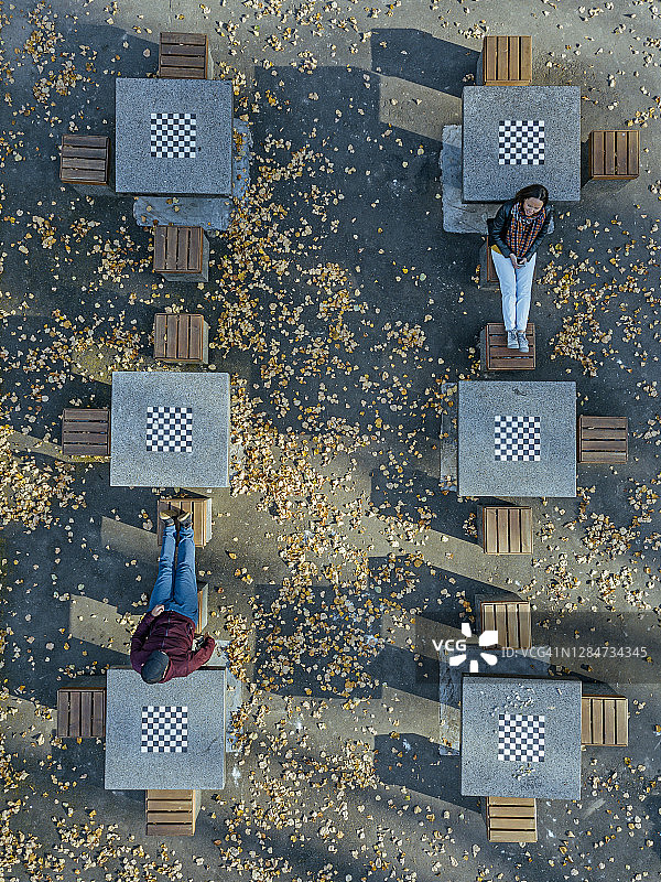 秋季，情侣在公园的棋桌旁放松图片素材